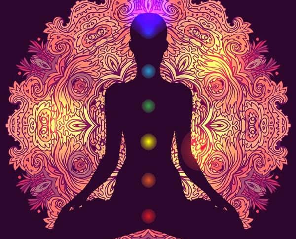 A silhouette in lotus pose with the seven chakras marked in colour over a mandala