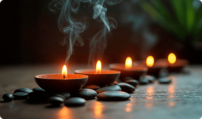 A row of lit tea lights on dark stones